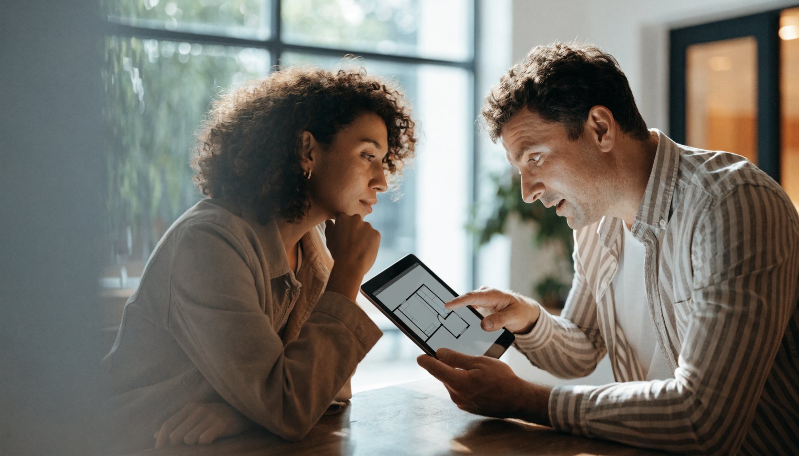 A GEEK consultant and a client reviewing a home floor plan on a tablet