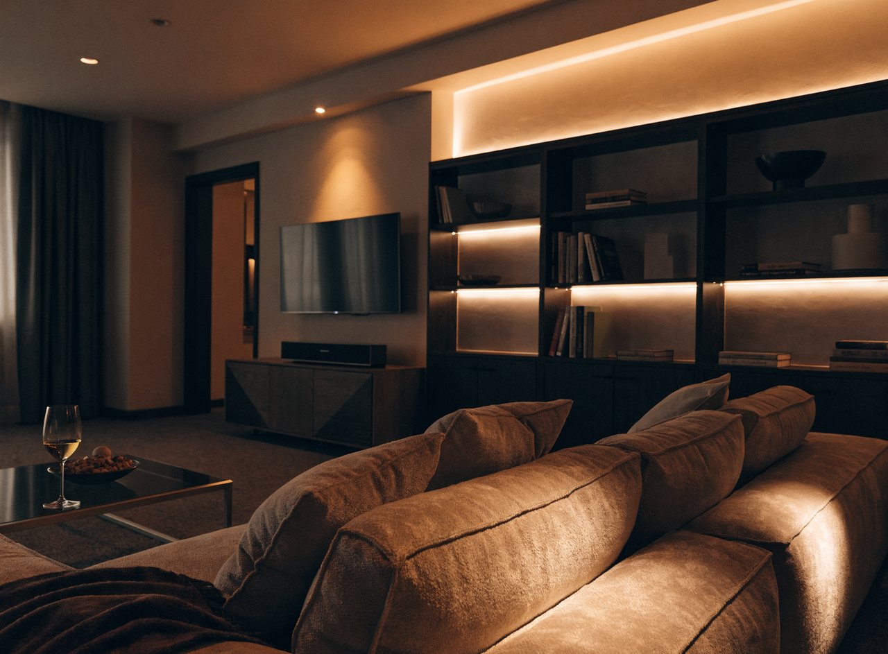 A living room set to a warm movie-night lighting scene with dimmed ambient light and glowing LED accents